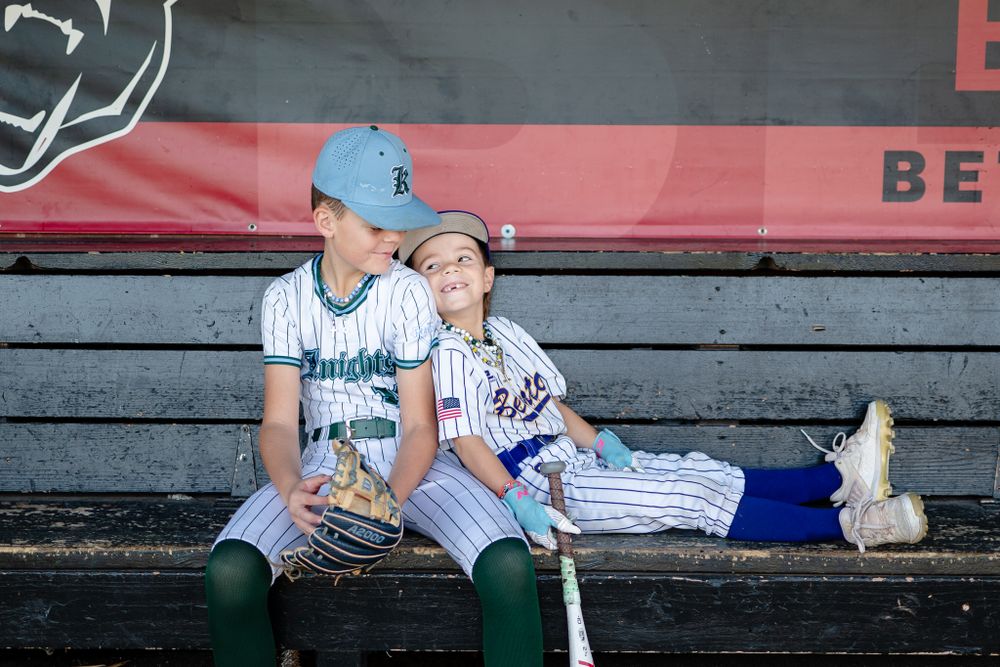 Players in baseball uniforms sitting together in dugout during game.