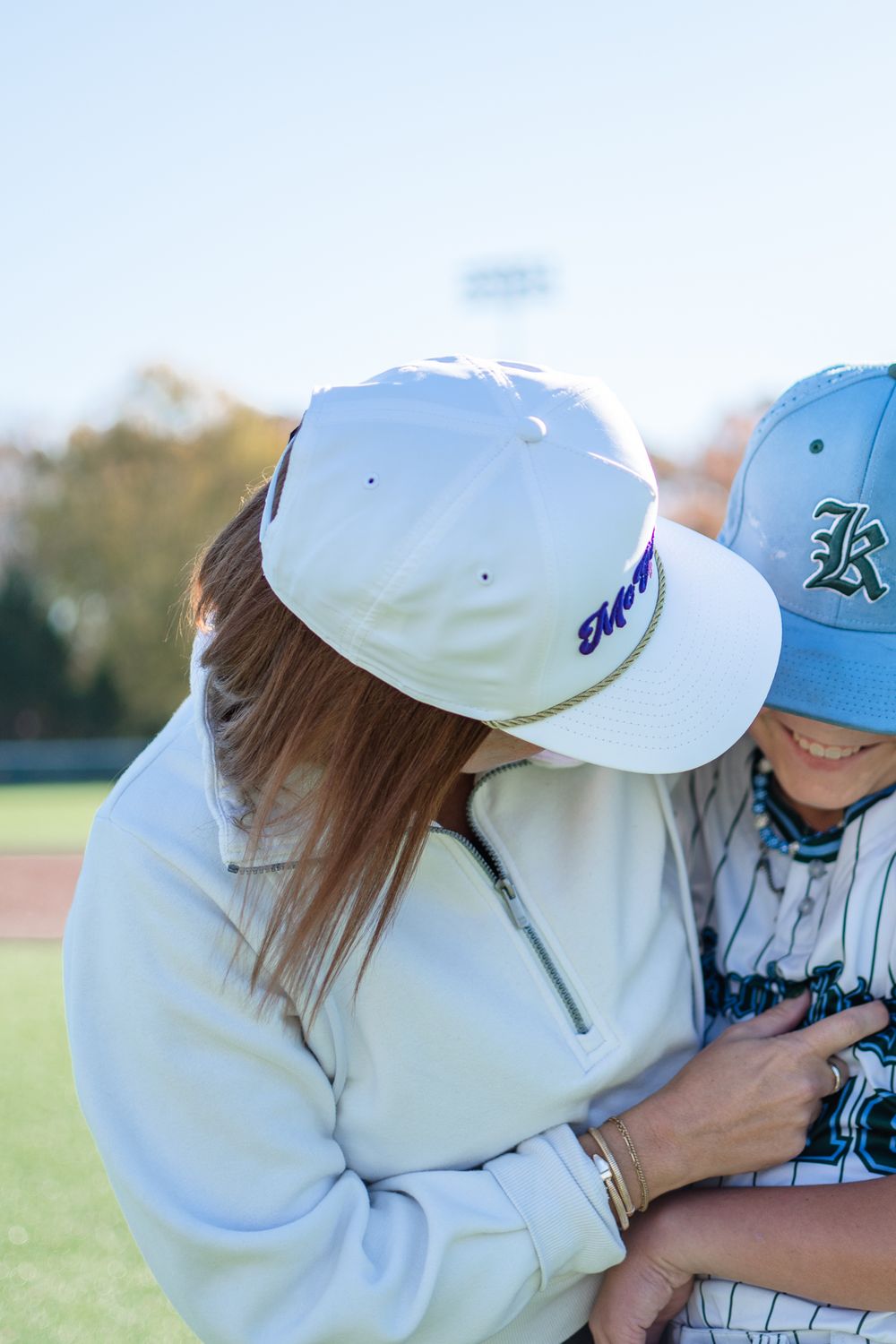 Baseball players wearing caps share a moment on sunny field during practice.