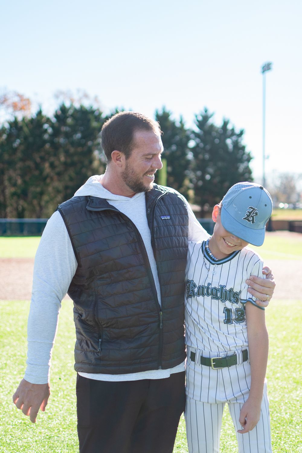 Baseball scene showing supportive interaction between players on sunny field.