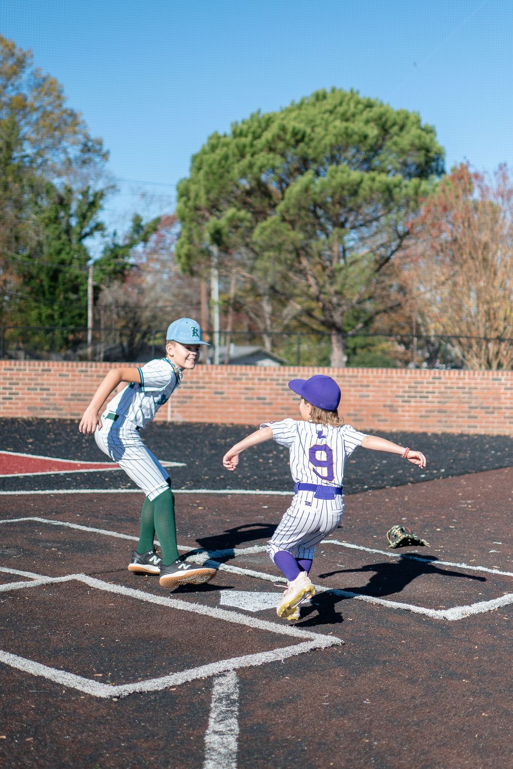 Young baseball players practice base running techniques on a baseball diamond.