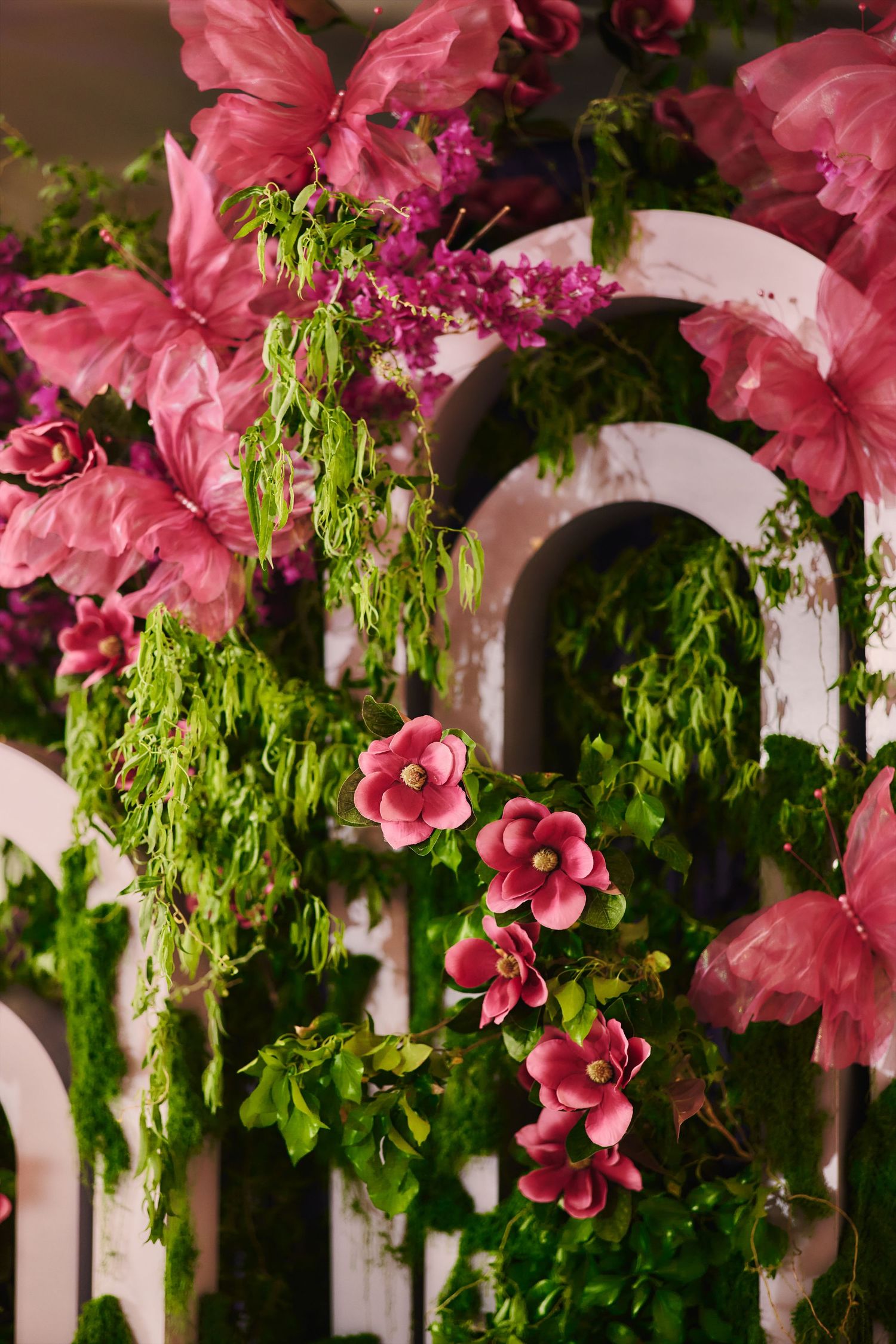 Pink flowers and green foliage cascade over a white fence, creating a romantic garden scene in close-up detail.