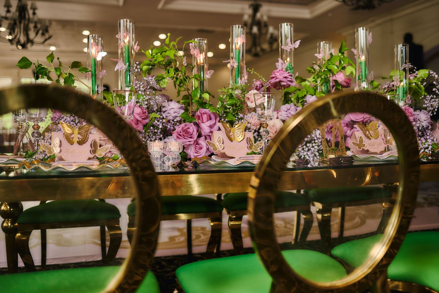 Elegant dining table setting with crystal glassware, purple floral centerpieces and ornate chairs viewed through circular frames.