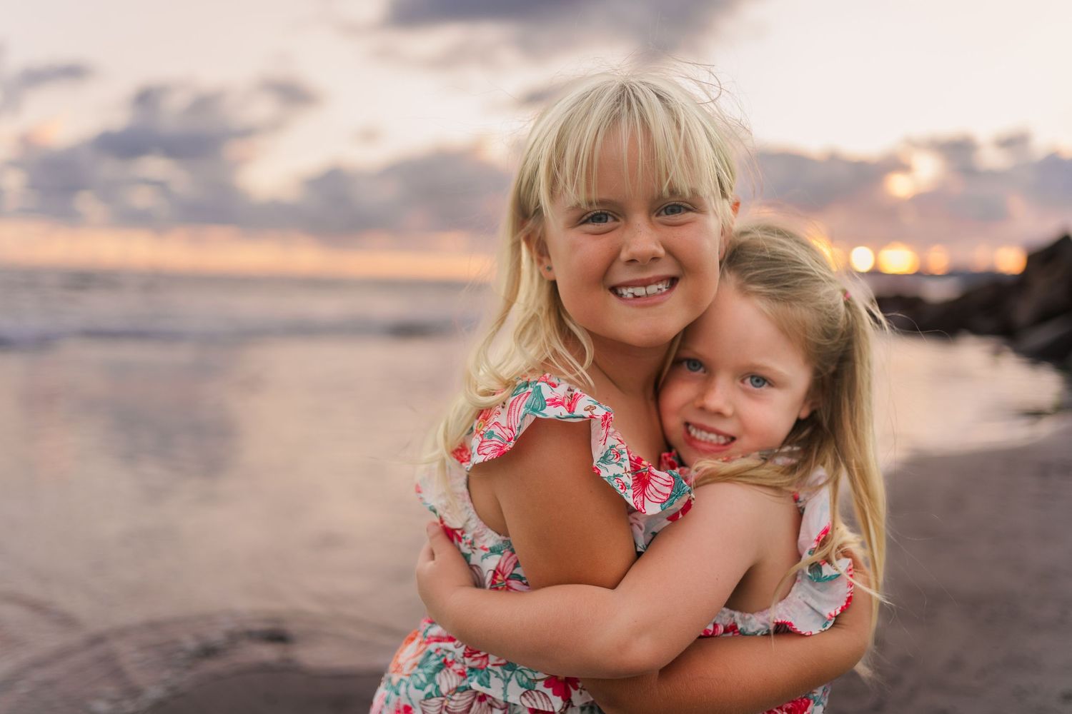 Sweet embrace on beach during golden sunset with ocean waves in background.