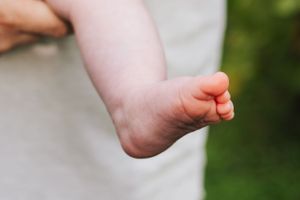 Close-up detail of baby feet against blurred green background.