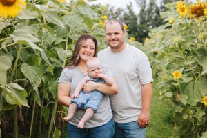A family poses together in a sunflower field during a summer photoshoot.