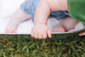 Close up view of tiny baby feet resting on the edge of a metal tub.