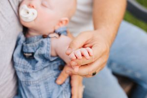 Close up of gentle hands holding and supporting a baby.