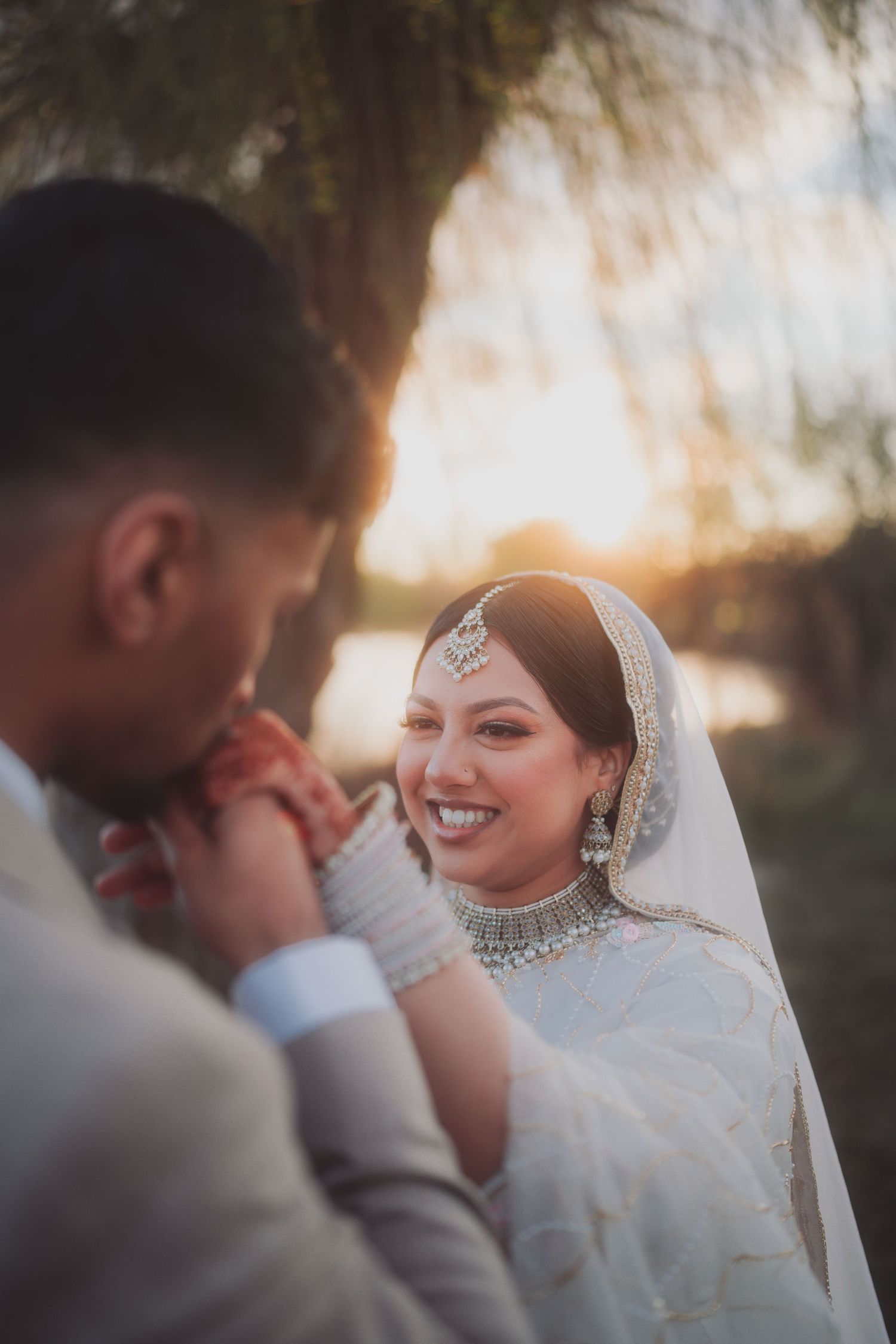 Romantic sunset wedding portrait with traditional South Asian bridal attire.