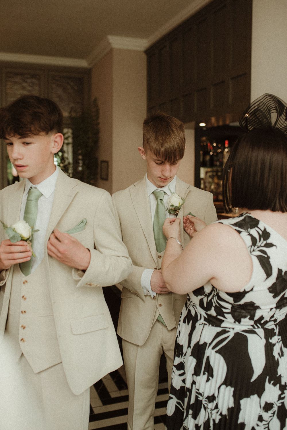 Two young ushers have their buttonholes pinned on by their mother ahead of their aunt's wedding ceremony.