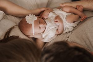 Series of intimate shots showing newborn baby in white outfit being cradled.