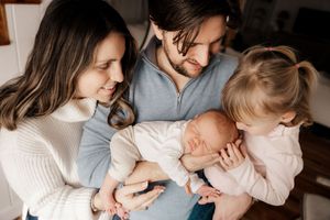 Candid family moment captured on couch showing affection and joy. Newborn photographer Southern Maine