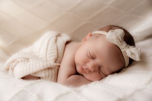 Peaceful sleeping newborn wrapped in white blanket shown from different angles.
