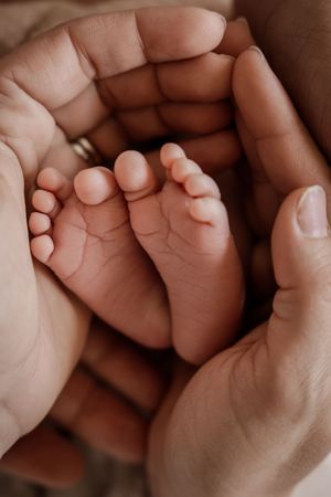 Close-up series of a tiny newborn baby hand grasping an adult finger in warm sepia tones.