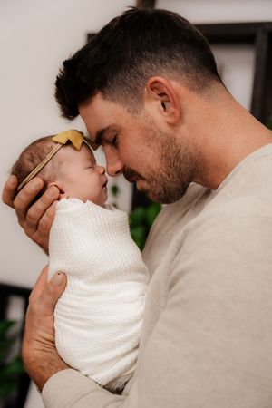 Tender moment with baby wrapped in white textured blanket.
