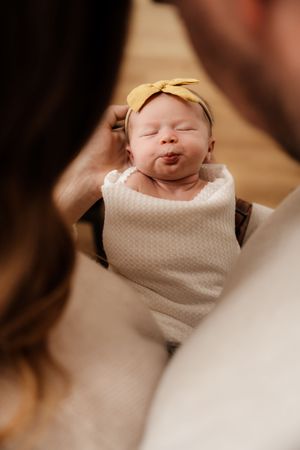 Peaceful newborn baby sleeping in white textured wrap.