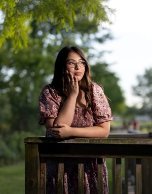 Outdoor portrait of model leaning on wooden fence at golden hour.