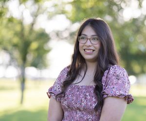 Outdoor portrait of upper half of the models body. Focusing on her soft smile. Taken at golden hour