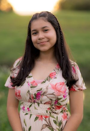 A person wearing a pink and white floral dress stands outdoors on a sunny afternoon. In Pearland, TX