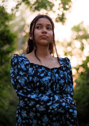 Model standing under the canopy of the trees. giving off a moody photograph.