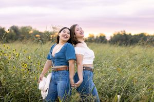 Two people in matching denim outfits share a joyful moment together in a wildflower meadow at sunset.