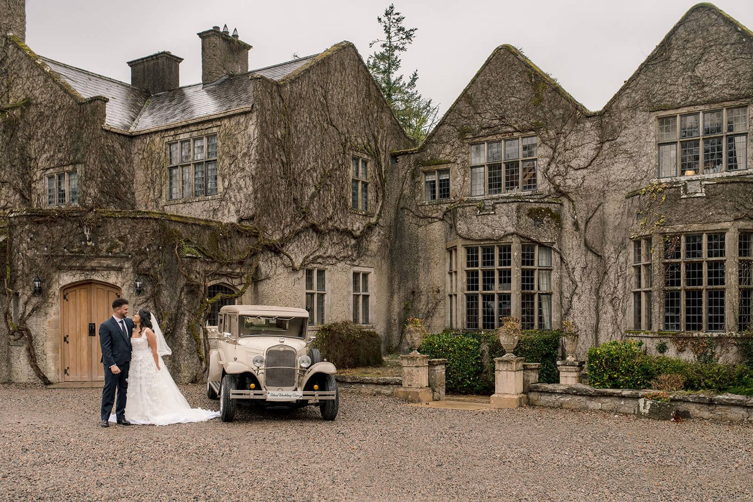 Vintage wedding car parked outside an ivy-covered stone manor house in county Leitrim.