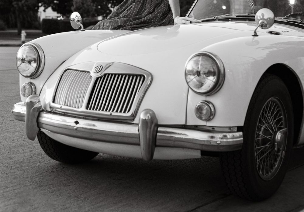 Black and white photo of a classic MGA vintage sports car with chrome bumper and wire wheels.