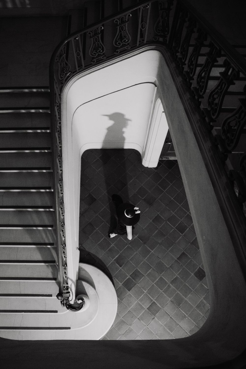 High-angle view of geometric patterns and shadows on tiled floor with dramatic lighting.