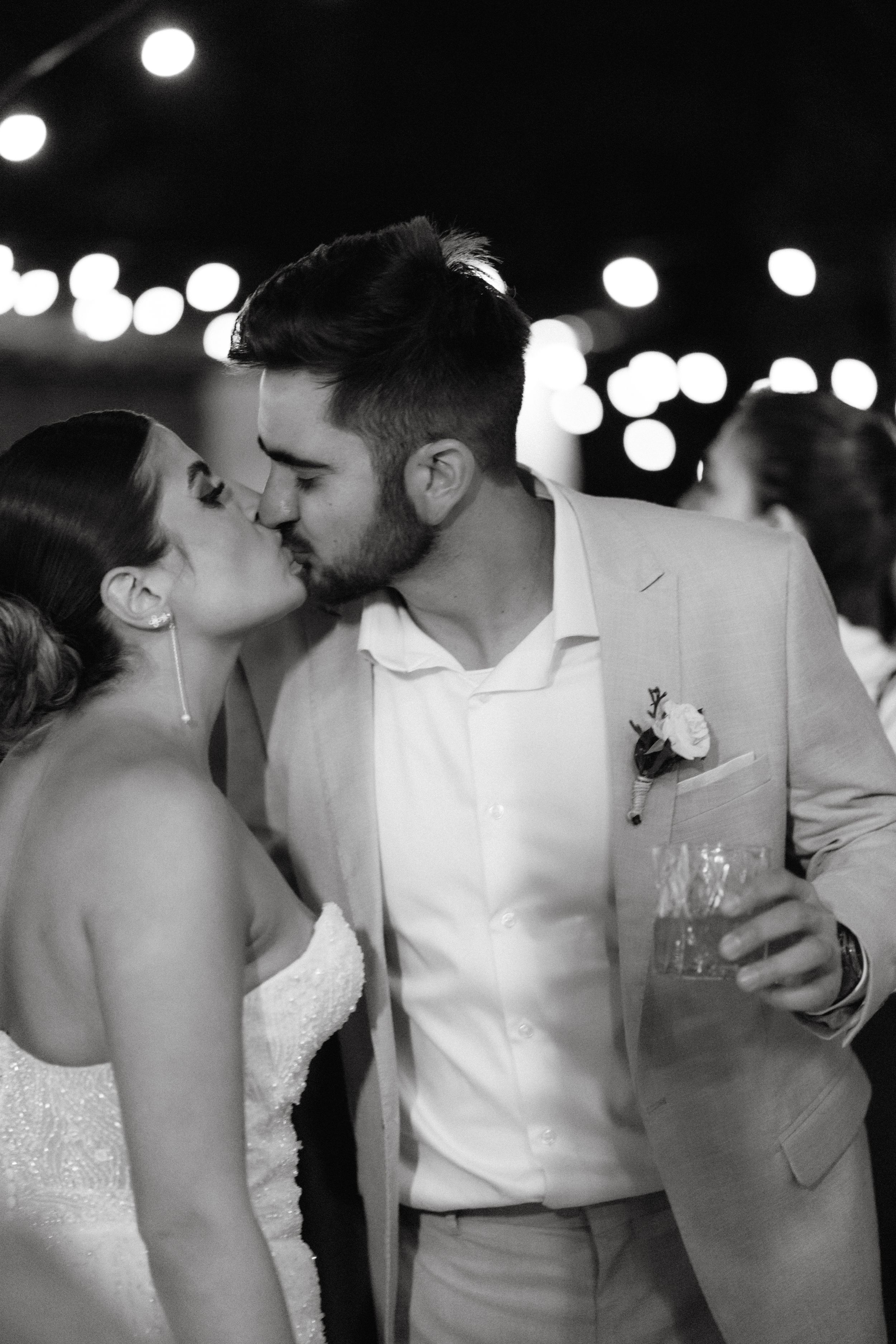 Romantic couple sharing intimate moments at a dimly lit evening celebration.