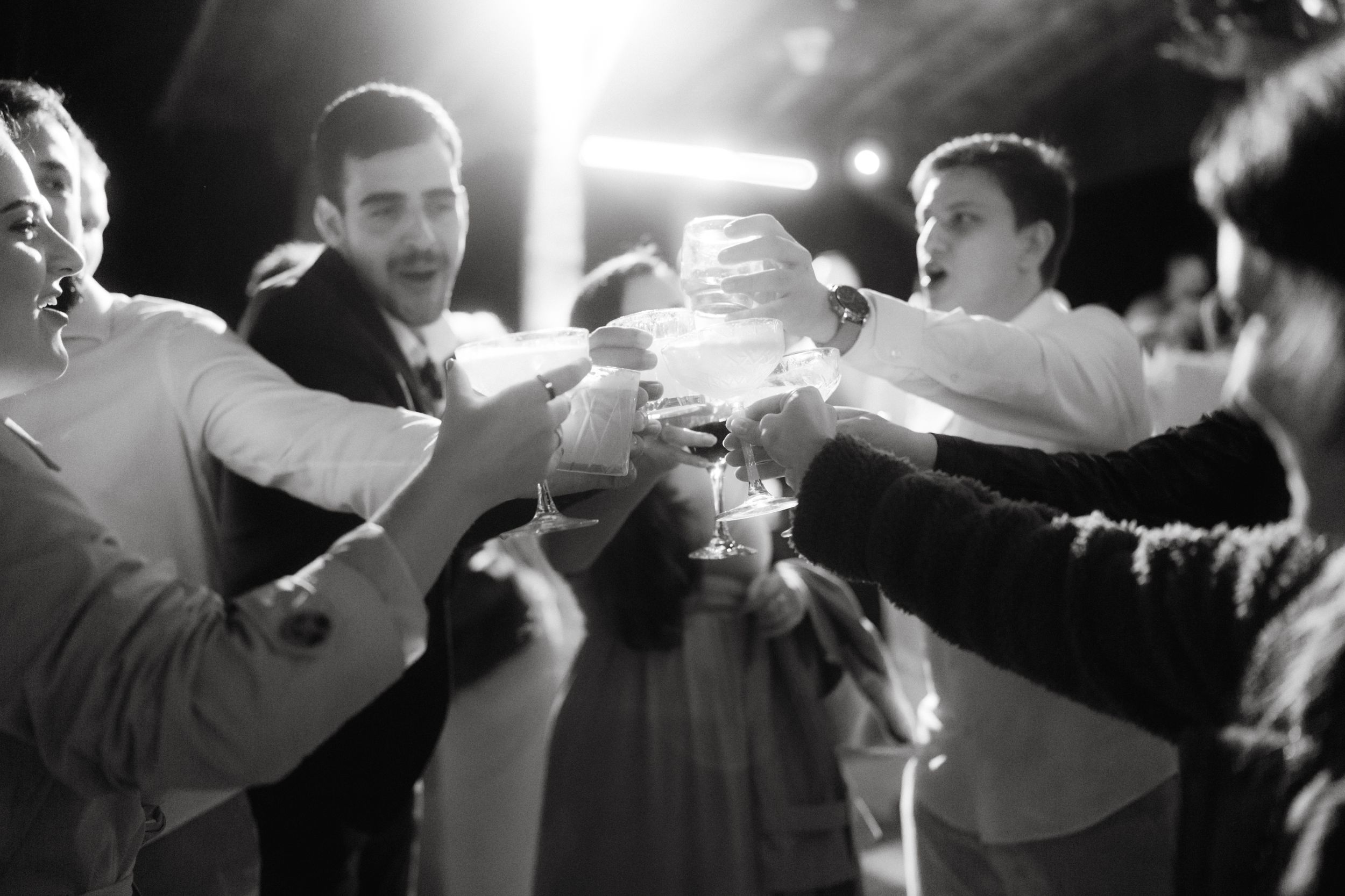 A group toasting with drinks during a nighttime celebration under bright lights.