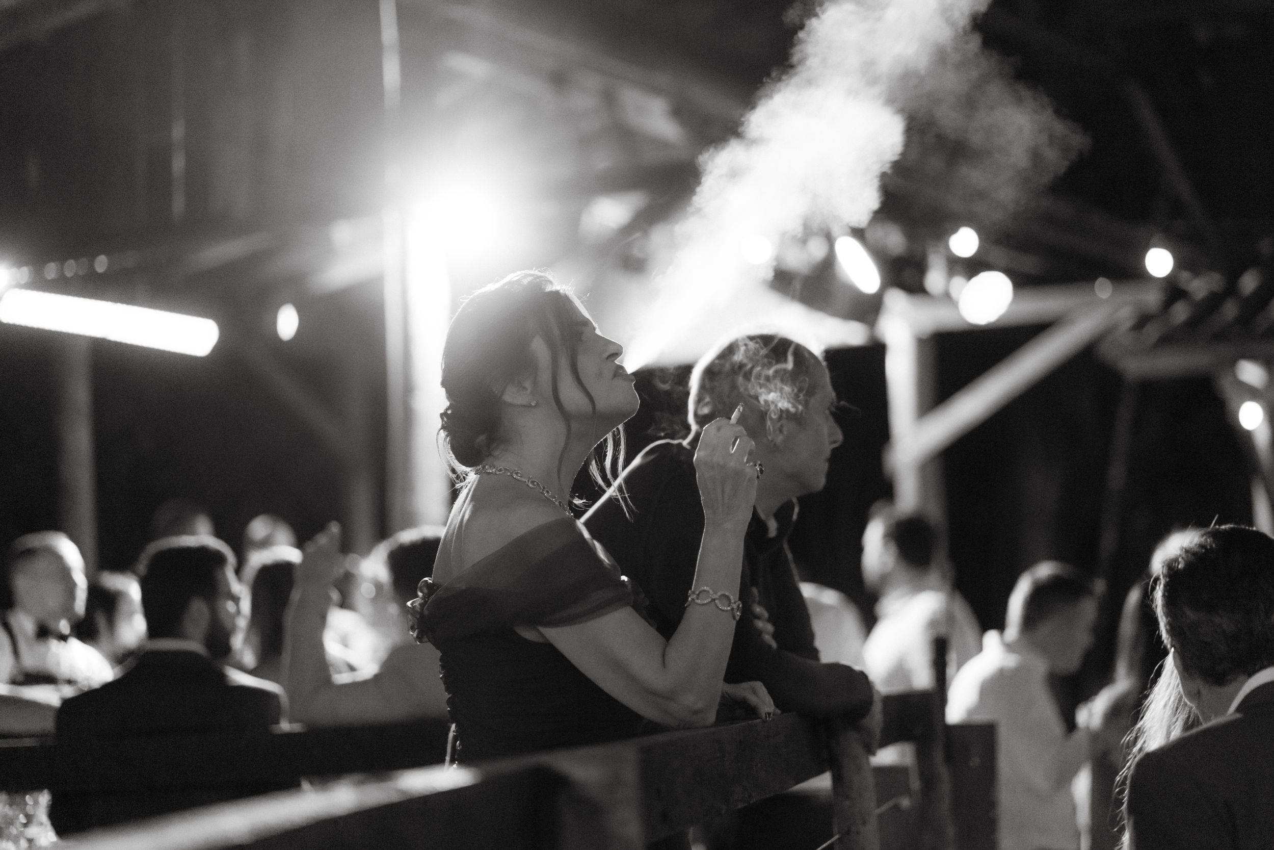 Smoky atmosphere in a dark nightclub with silhouettes of people dancing under spotlights.