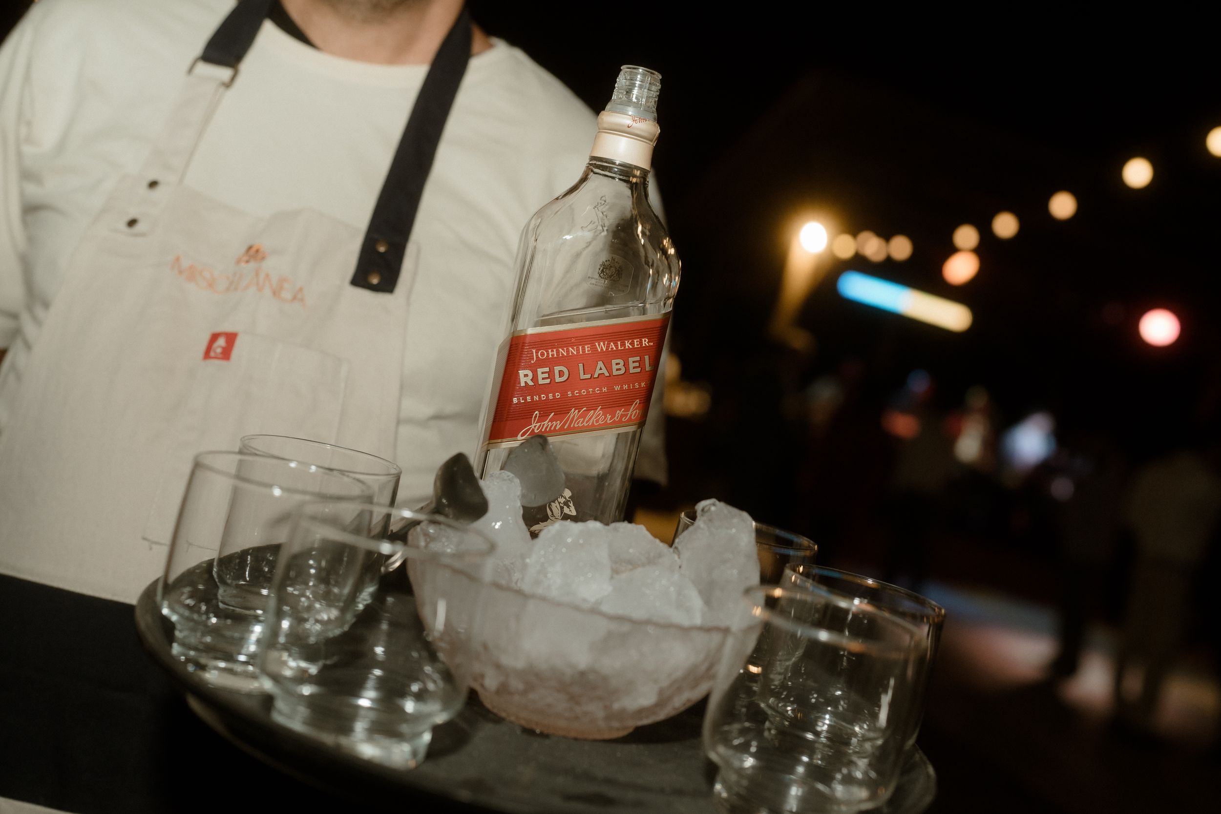 Dark nighttime reception setting with empty glasses and bottles on tables.