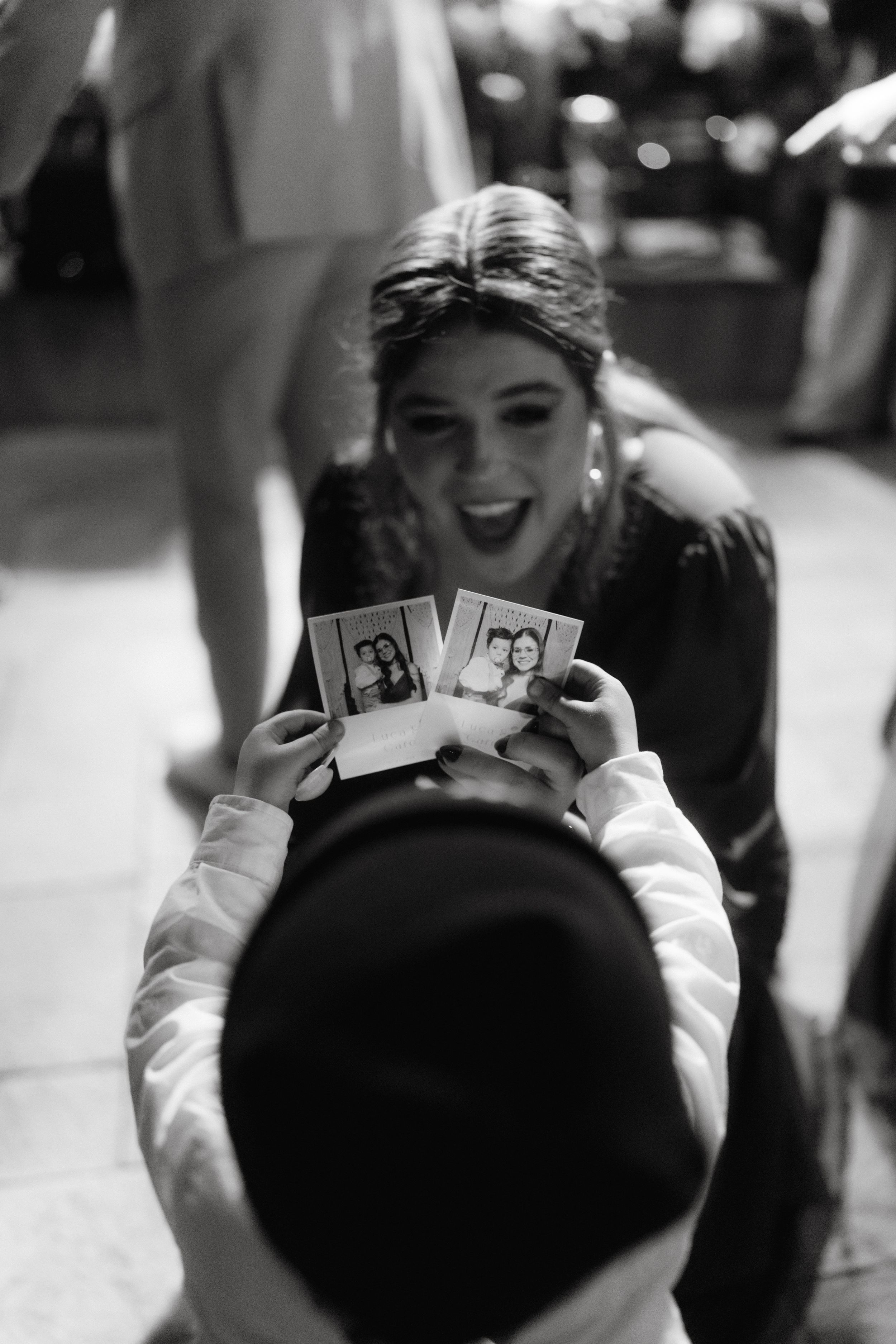 Guest holding up polaroid photos at a wedding reception celebration.