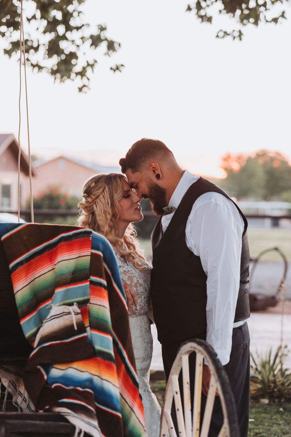 A romantic moment near a vintage wagon decorated with a colorful striped blanket at dusk.