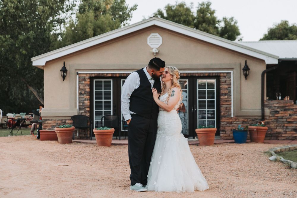 Romantic wedding portrait in front of rustic brick building at sunset.