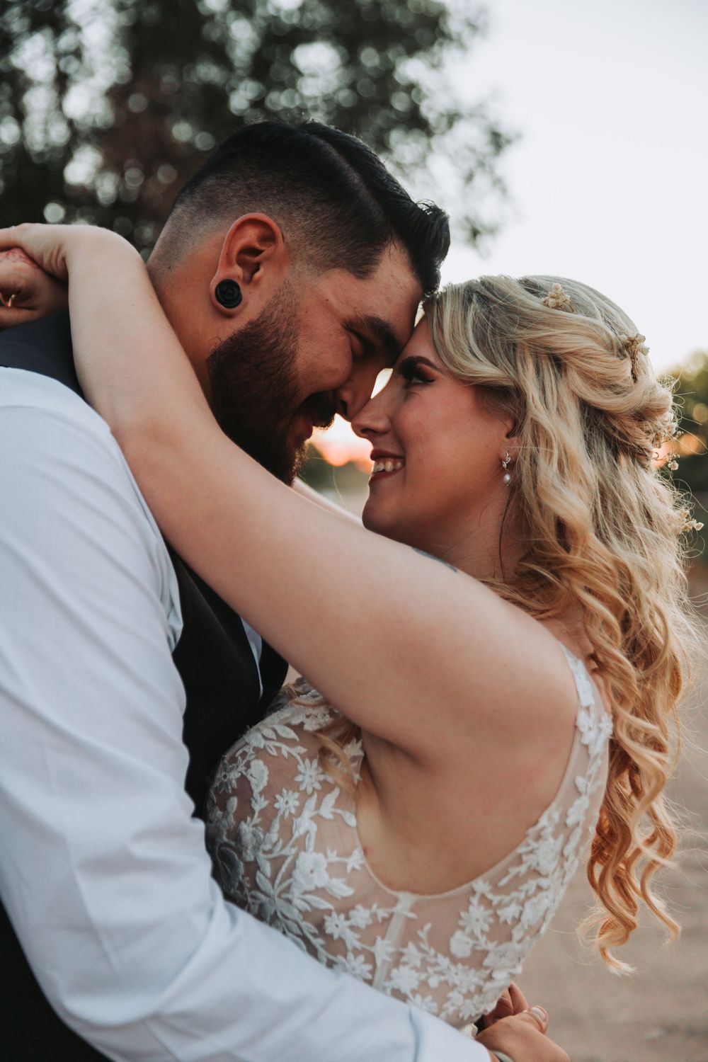 An intimate moment between newlyweds during their wedding photoshoot at sunset.