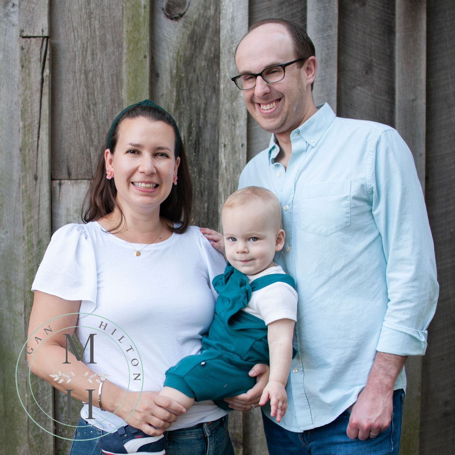 standing family of 3 pose near gray barn