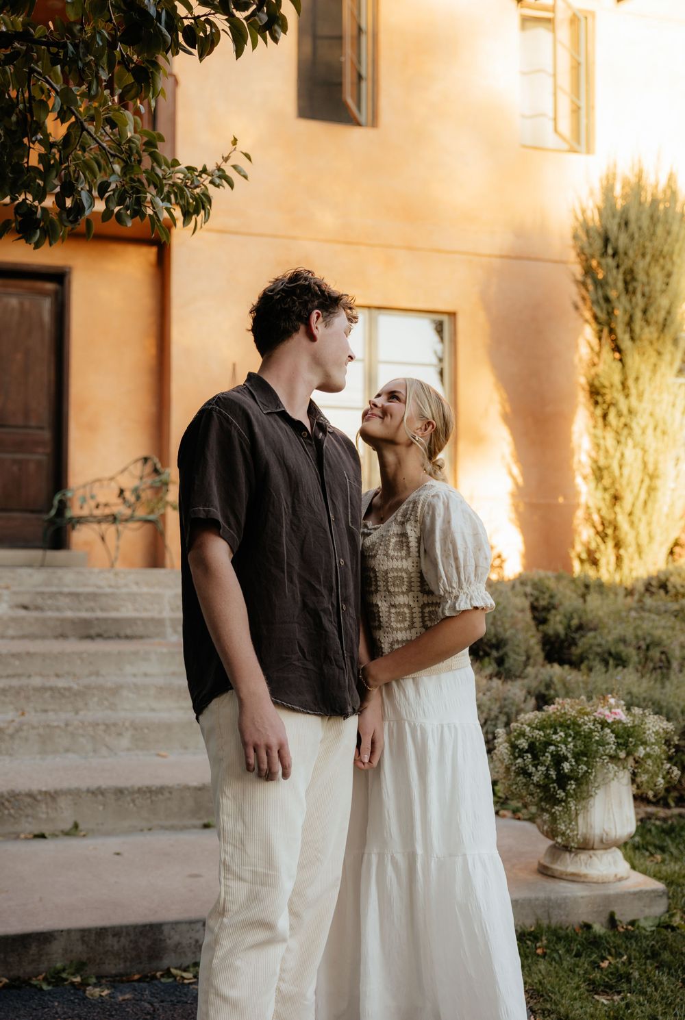 Couple sharing a romantic moment outside a golden Mediterranean villa in golden hour light.