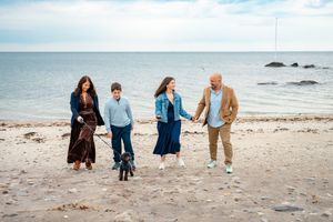 A group walks together holding hands along a peaceful beach shoreline.