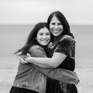 A series of black and white photos showing two people hugging and laughing together outdoors.