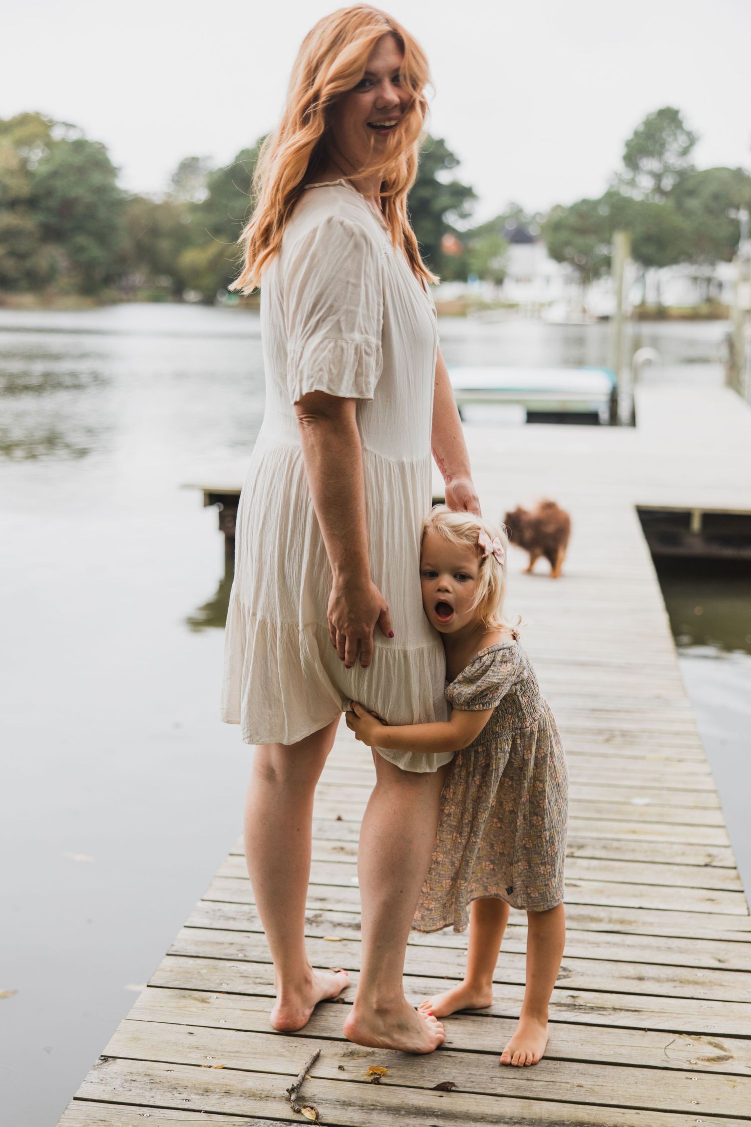 Sweet candid moment of parent and child hugging on lakeside dock.