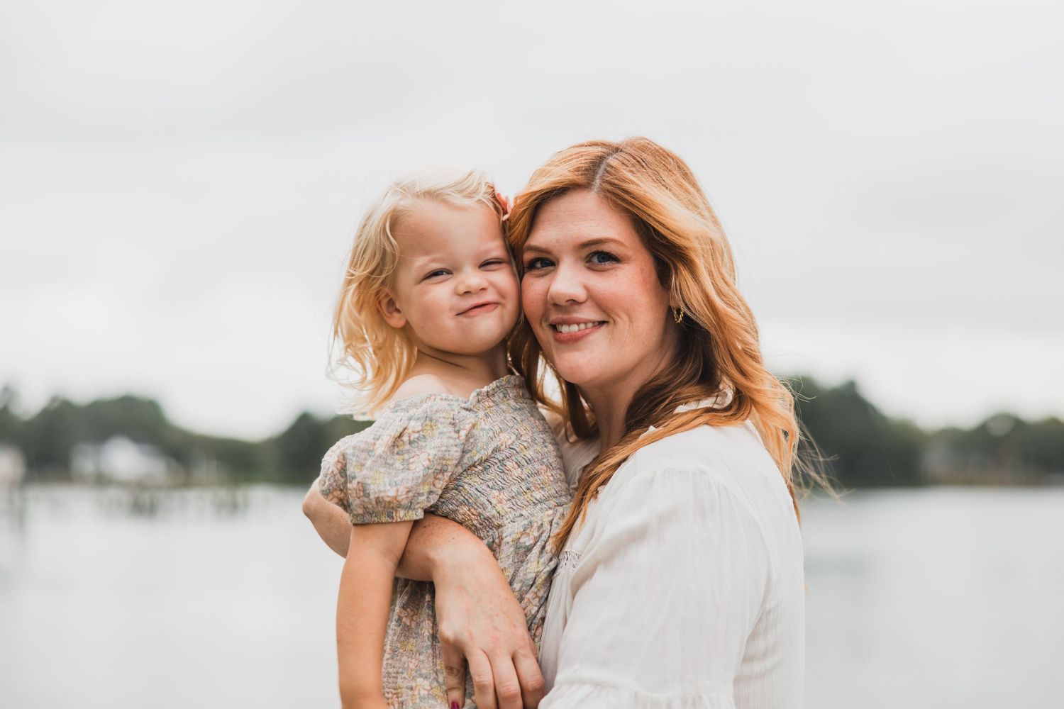 Tender outdoor portrait of parent and child against waterfront backdrop.