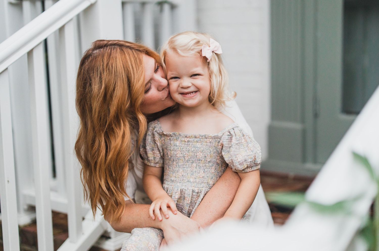 Tender outdoor portrait on white porch steps with soft natural lighting.