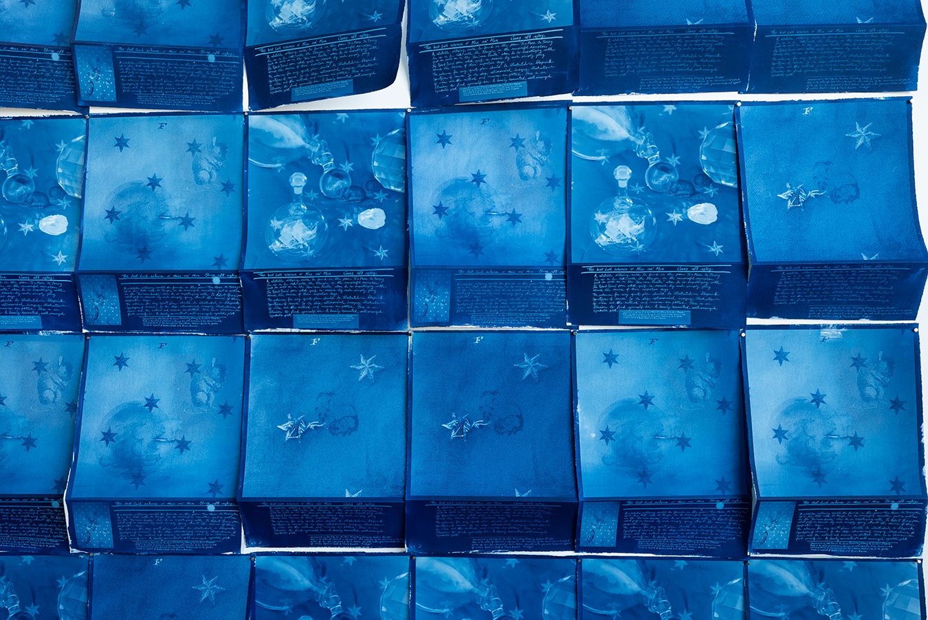several cyanotypes installed on a wall with a bend in the print