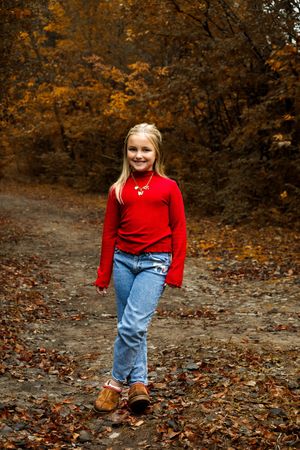 A sequence of photos showing someone in a red sweater and jeans walking through autumn leaves on a forest path.