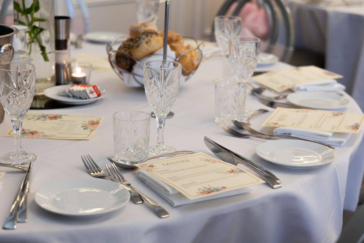 Sydney Event Photography - An elegant table setting with crystal glasses, white plates, and silverware on a white tablecloth.