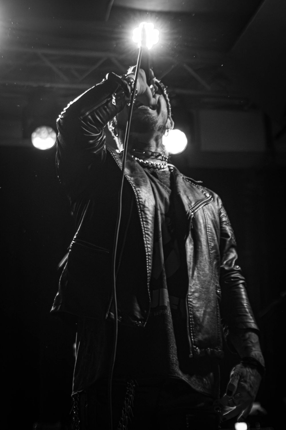 Performer in leather jacket silhouetted against stark venue lighting.