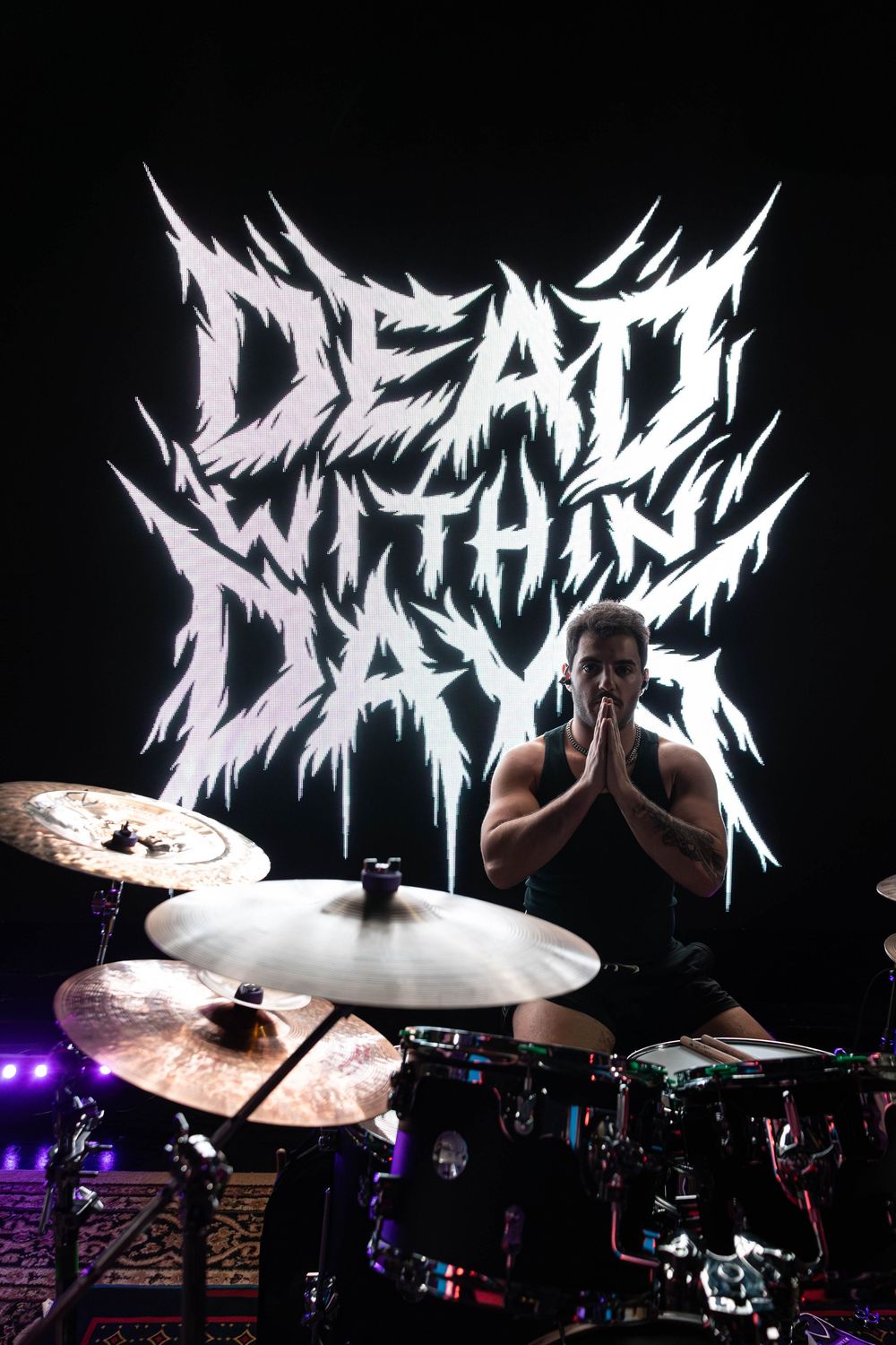 Metal band logo illuminated in white against dark background during live performance.