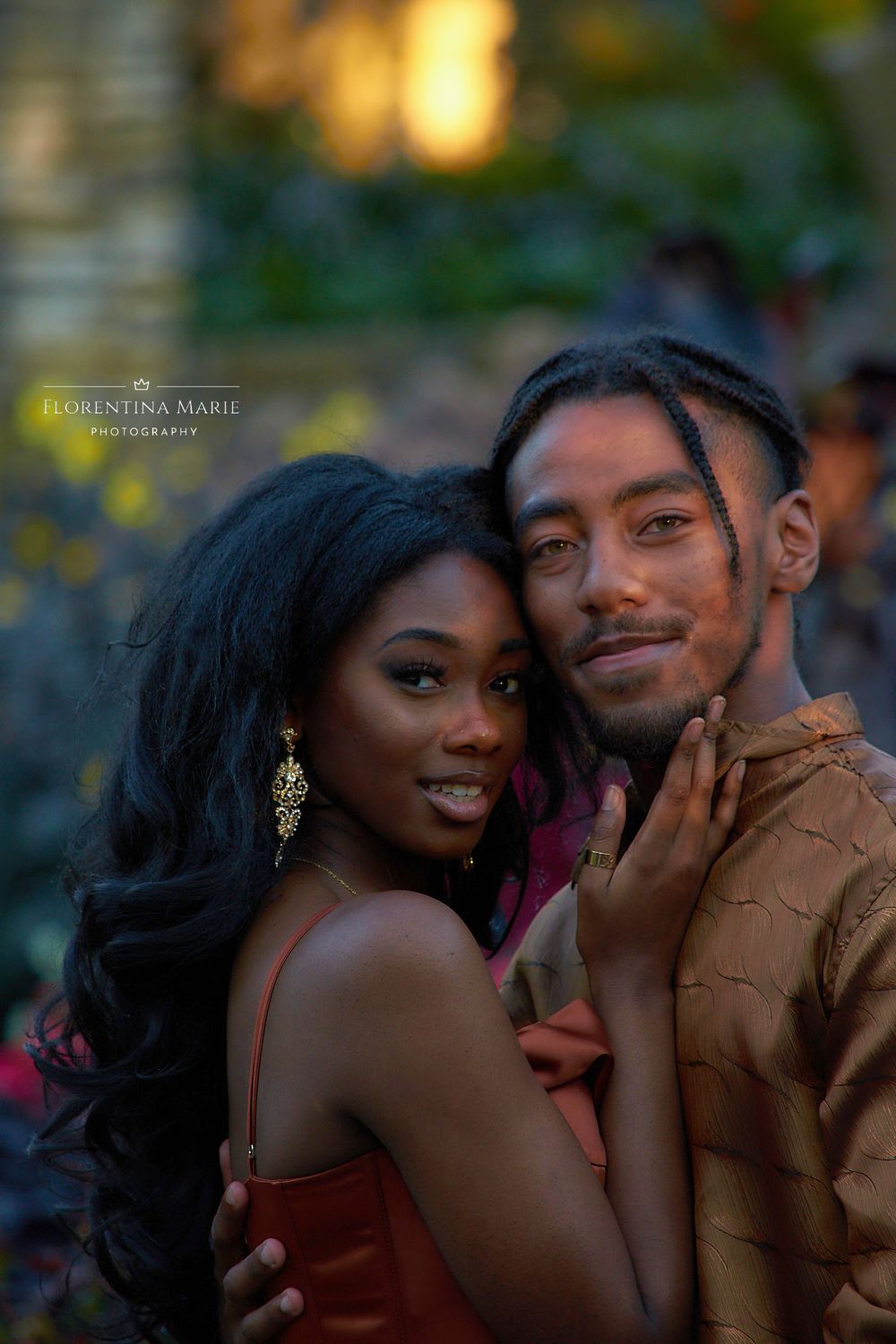 A couple poses intimately for a portrait in a garden during golden hour.