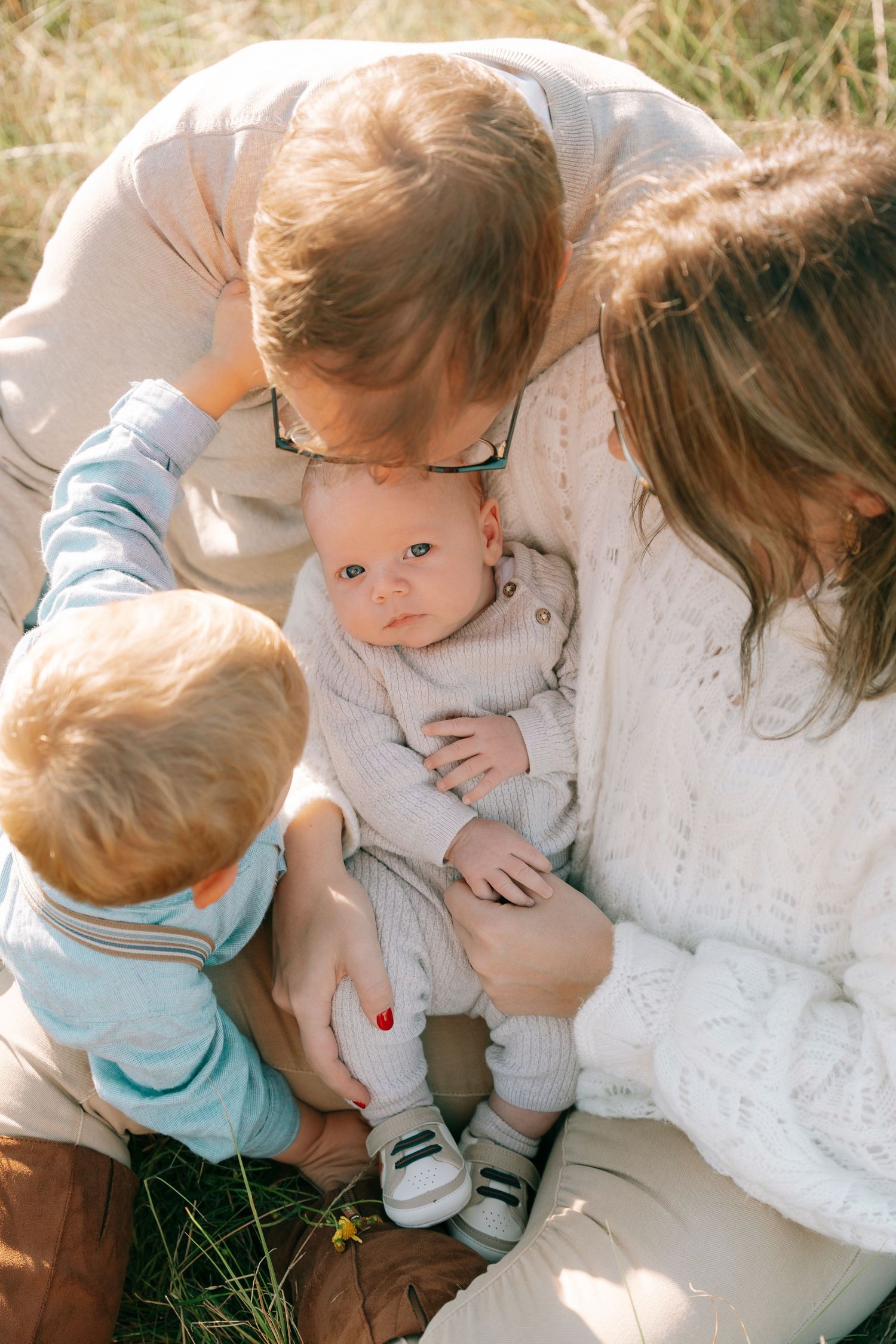 Intimate family moment outdoors with baby and toddler.