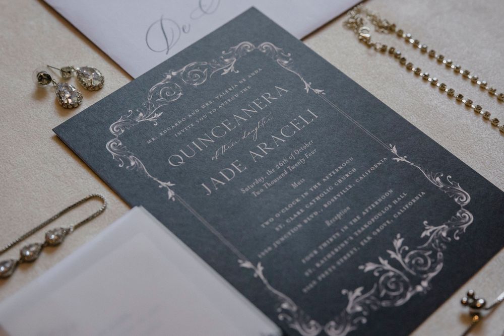 Elegant dark gray wedding invitation with ornate vintage-style border details and text.
